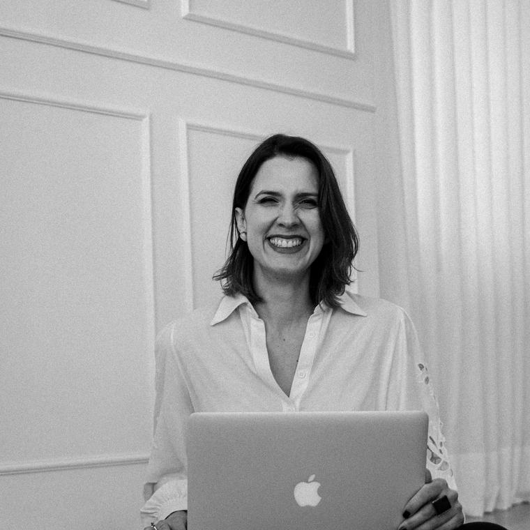 Luana Duvaresch sorrindo, sentada no chão com o notebook